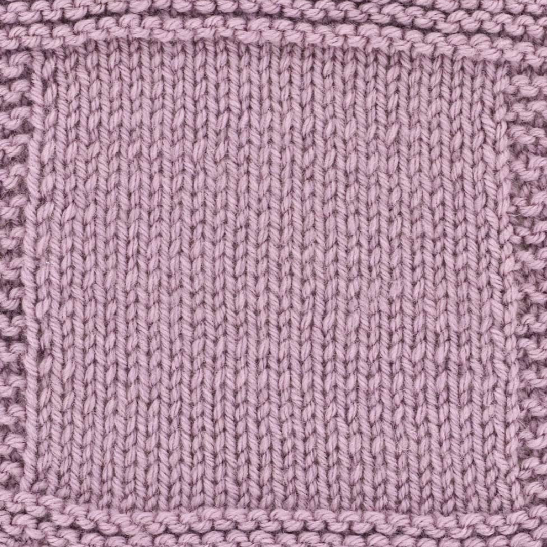 A handknit swatch of Debbie Bliss Cashmerino DK yarn in shade Lilac. It is a soft, muted purple color.