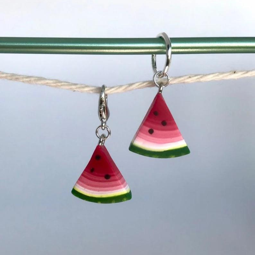 Two polymer clay watermelon slice stitch markers hang on a string.