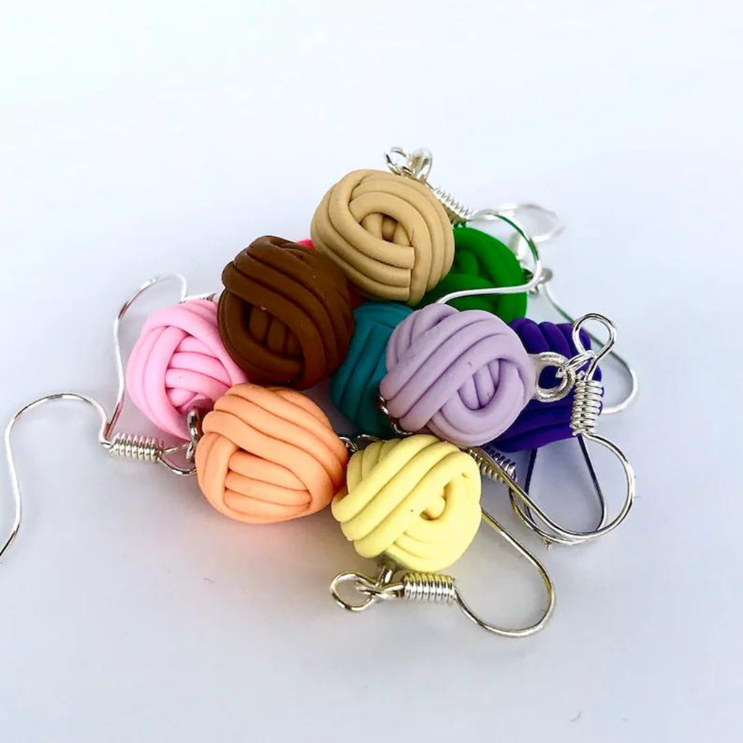 A pile of polymer clay yarn ball earrings in various colors.