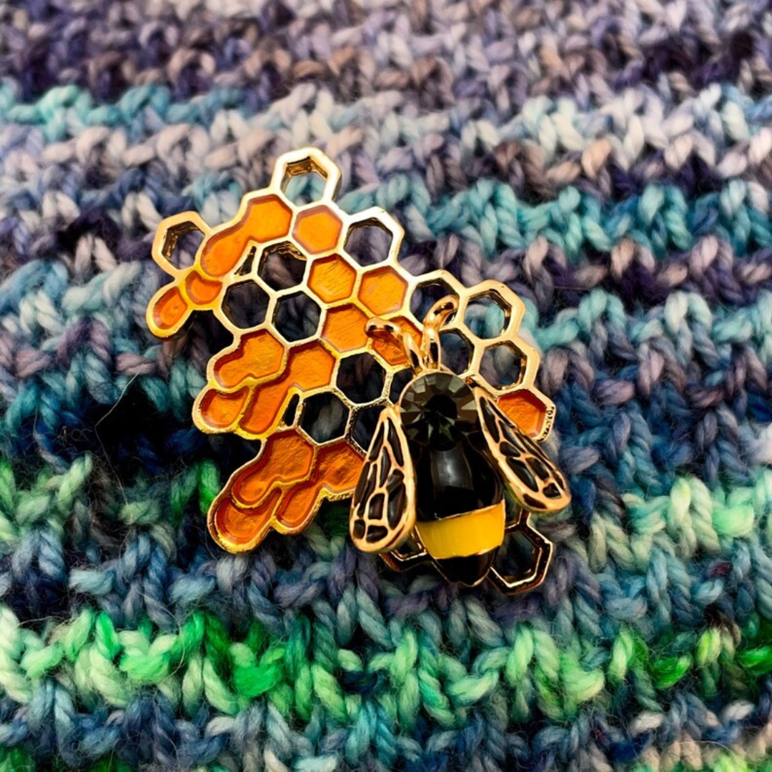 Bee on honeycomb brooch pinned on a variegated handknit fabric.
