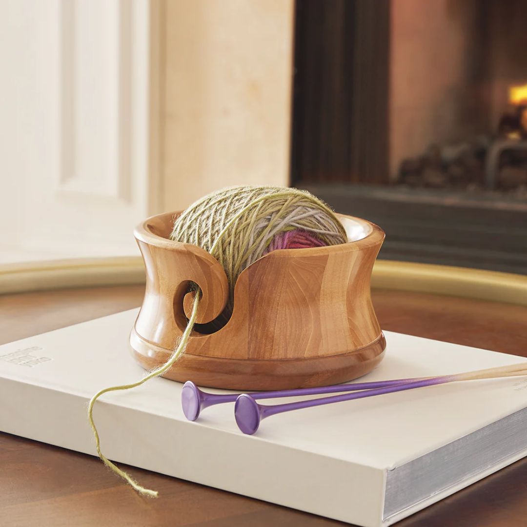A yarn bowl with a slightly flared top and smooth, multi-tone wood finish.