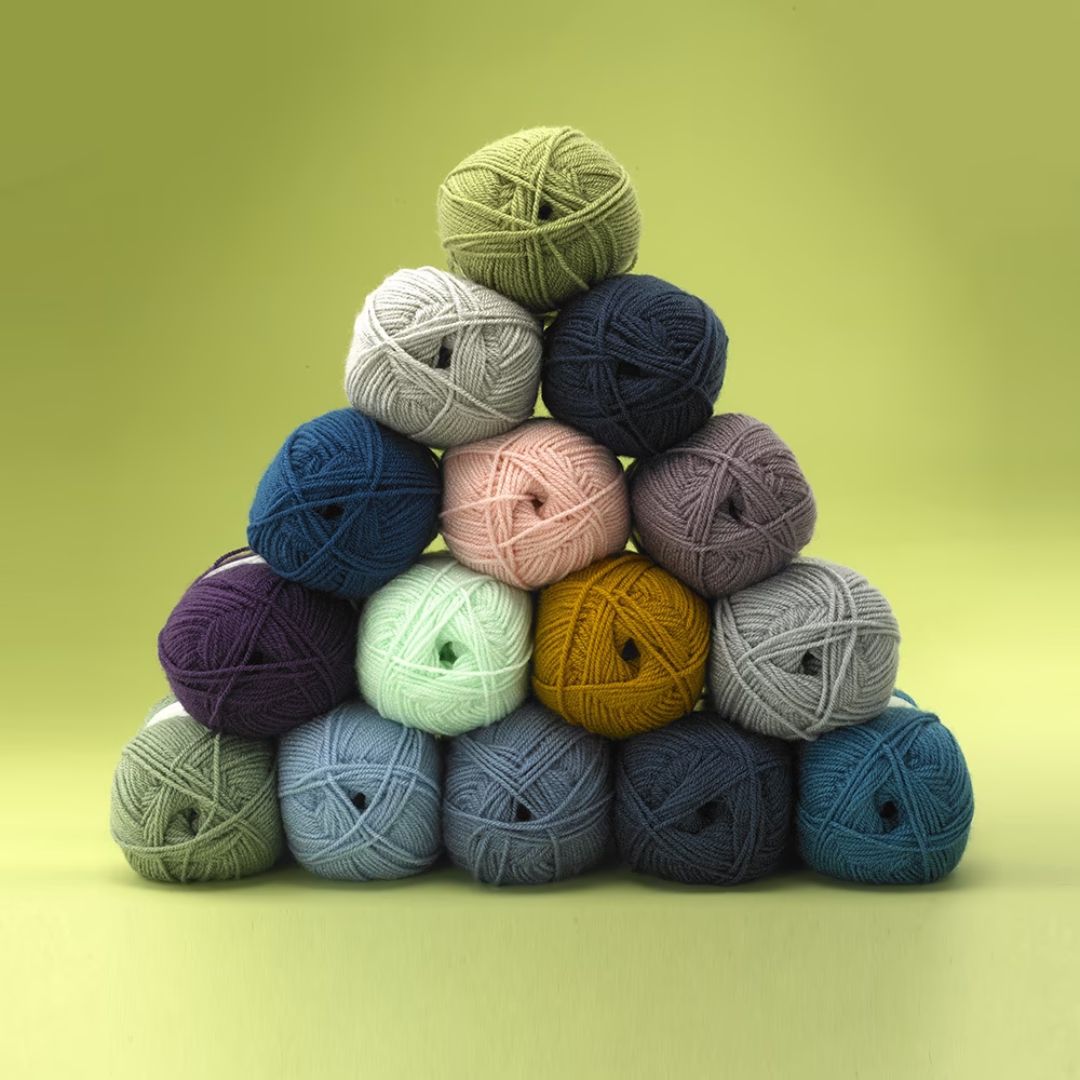 A pile of skeins of yarn in various colors stacked up into a triangle shape.