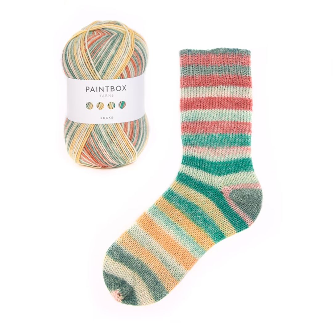 A skein of variegated yarn next to a striped handknit sock made with that same yarn.