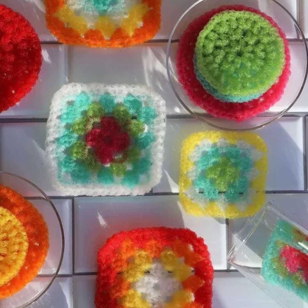 A set of brightly colored crochet granny squares and granny stitch circles made using Lion Brand Stitch Soak Scrub yarn.