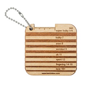 A small wooden tool with grooves to measure the thickness of yarn.