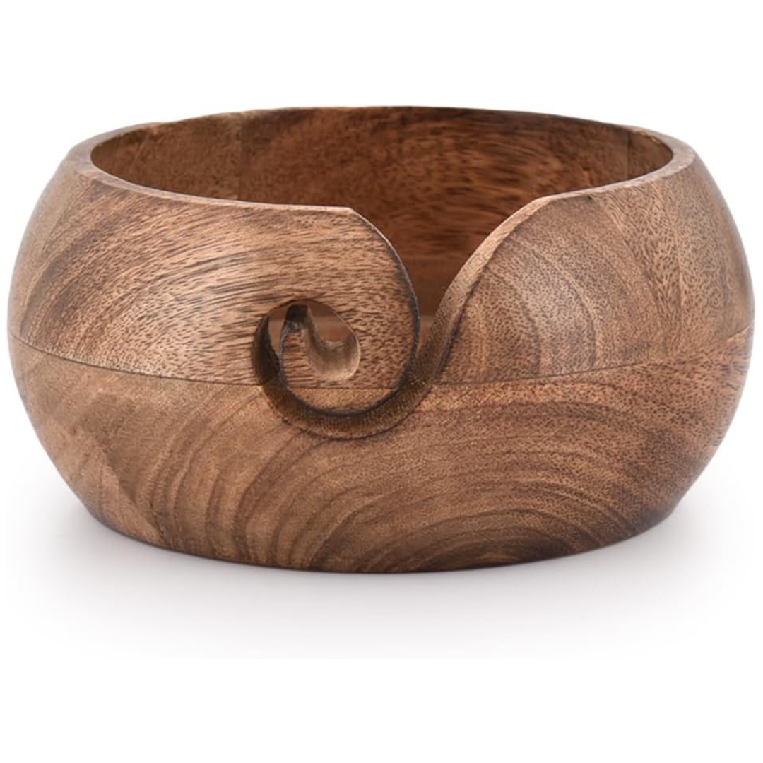 A brown wooden yarn bowl with a swirl cutout in the side to put your yarn through.