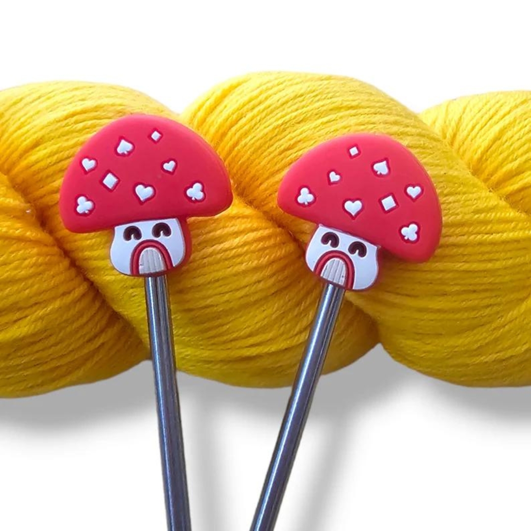 A set of knitting needle point protectors that look like red and white mushroom houses.