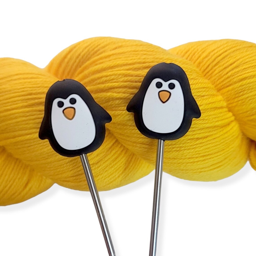 A set of knitting needle point protectors that look like little penguins.
