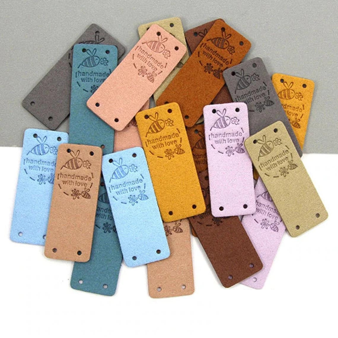A collection of many rectangle leather labels with small bees around the words "handmade with love".